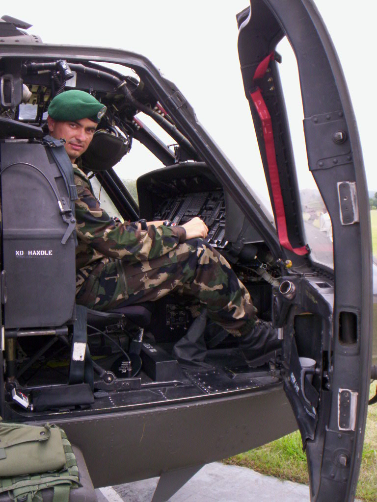 Joseph Matthew Hajczinger in camouflage uniform and green beret sitting in the cockpit of a military helicopter at Fort Bragg's John F. Kennedy Special Warfare School in 2006.